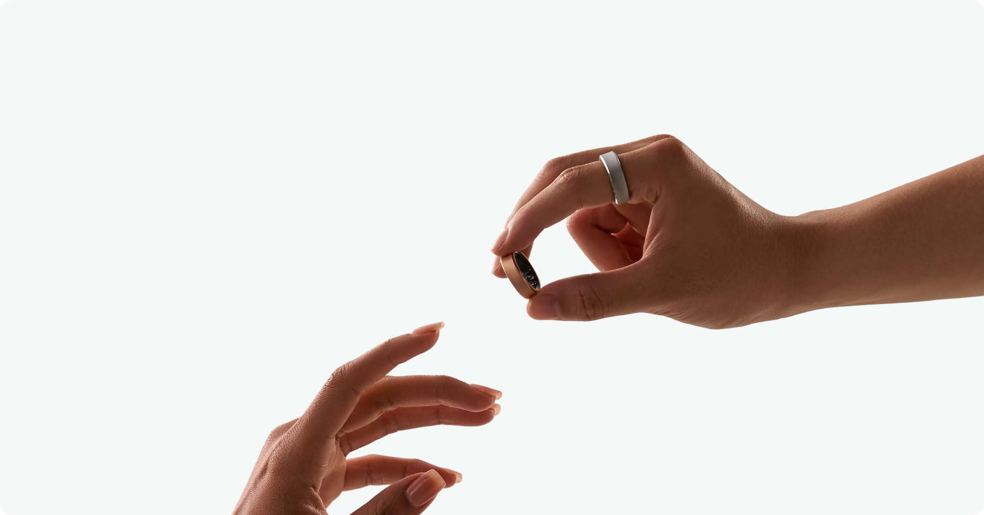 RingConn Gen 3 official press image: a hand wearing the silver ring holds the gold variant between two fingers, against a white background